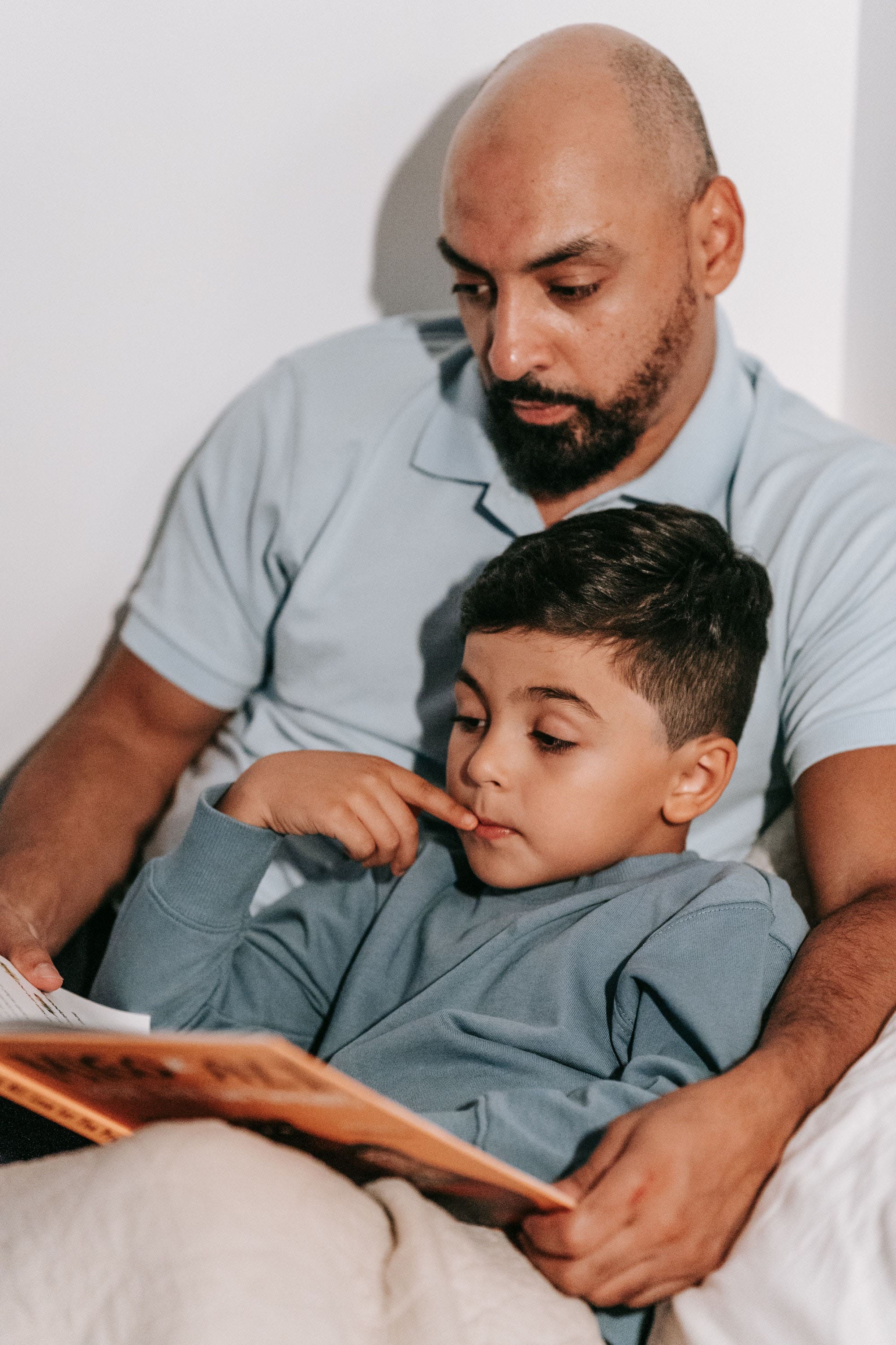 man reading book to son